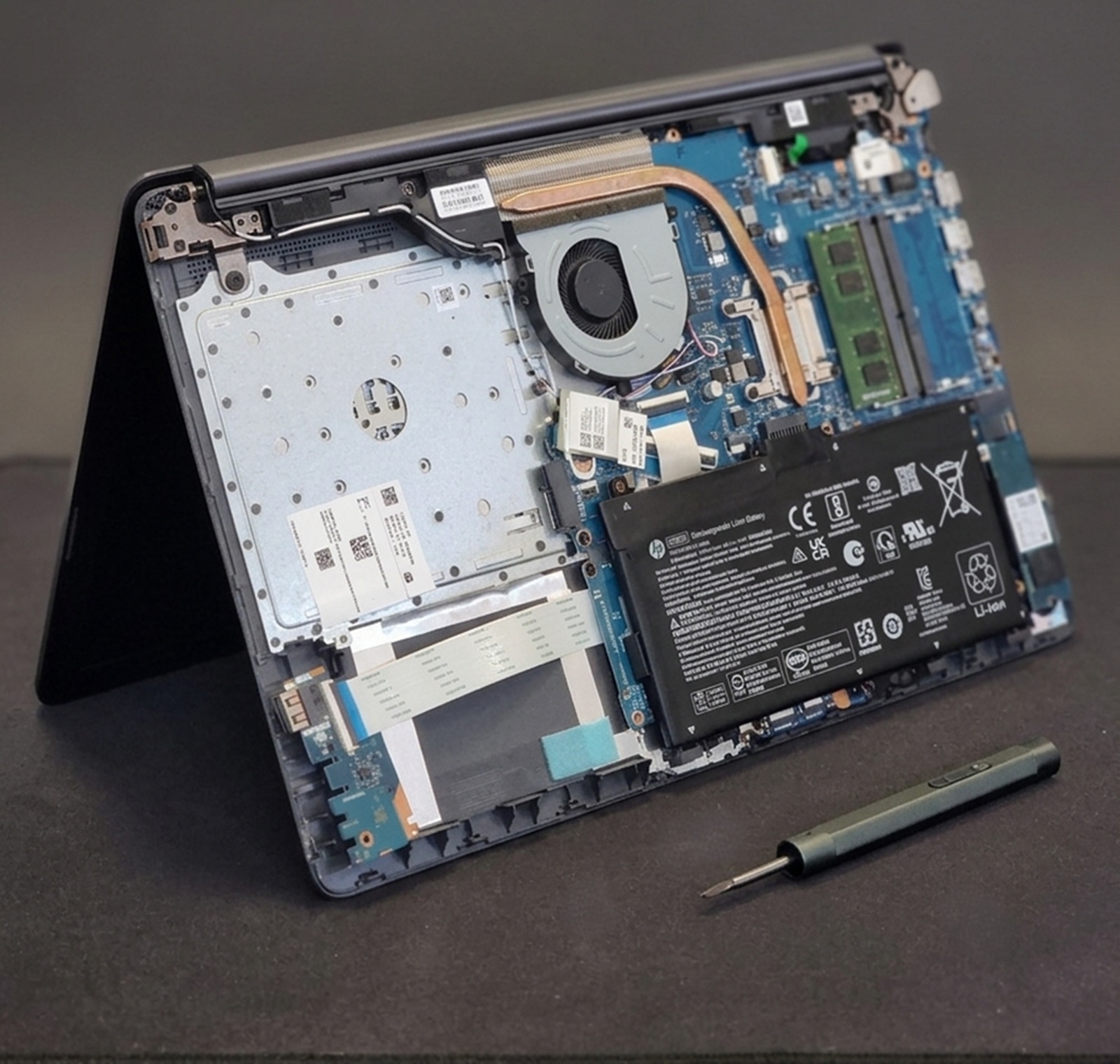 Szétszerelt HP laptop belső szerkezete alaplapi javítás és diagnosztika közben precíziós csavarhúzóval az MPC Szerviz kecskeméti műhelyében.